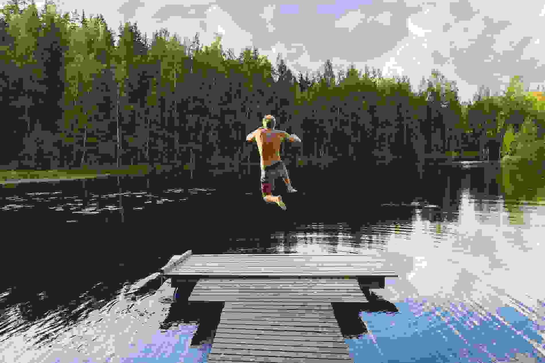 Man in shorts jumping into a lake