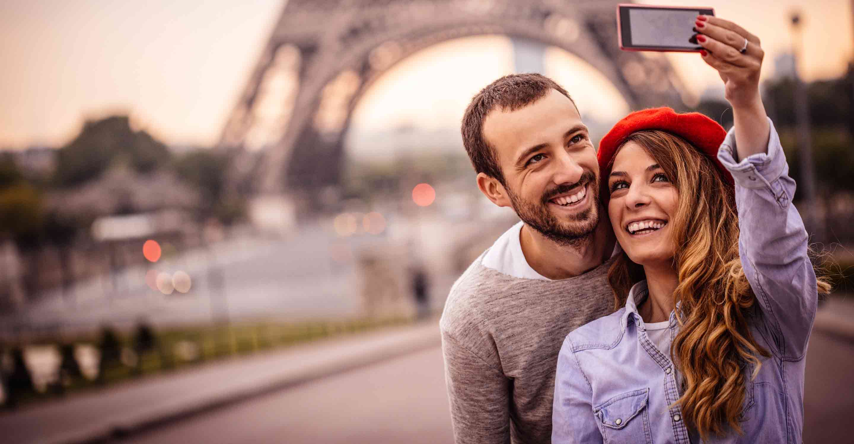 Smiling couple taking selfie in front of Eiffel Tower