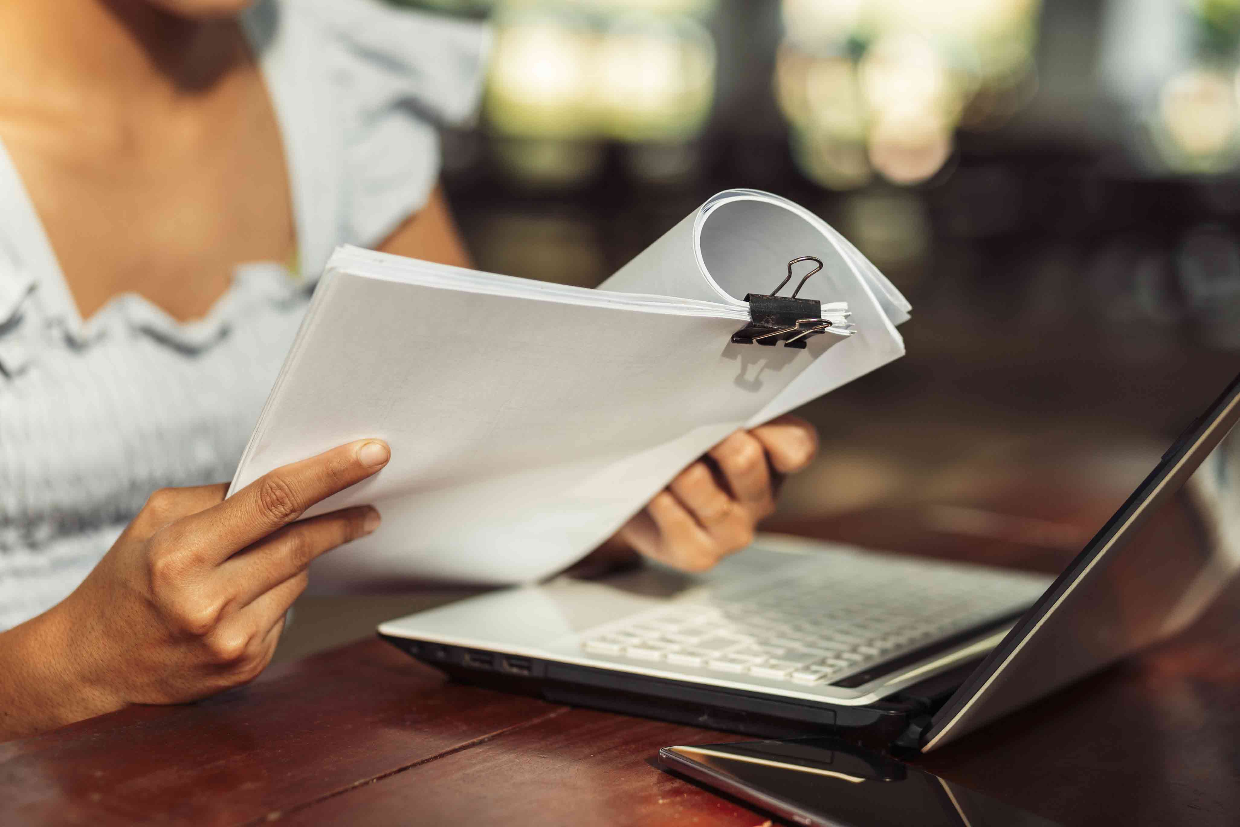 woman looking over documents and laptop