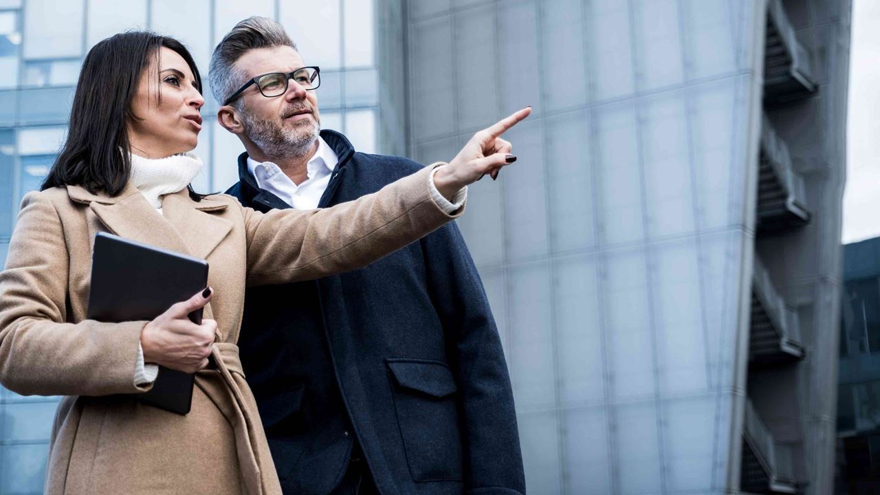 business-woman-pointing-to-distance-as-businessman-looks-on