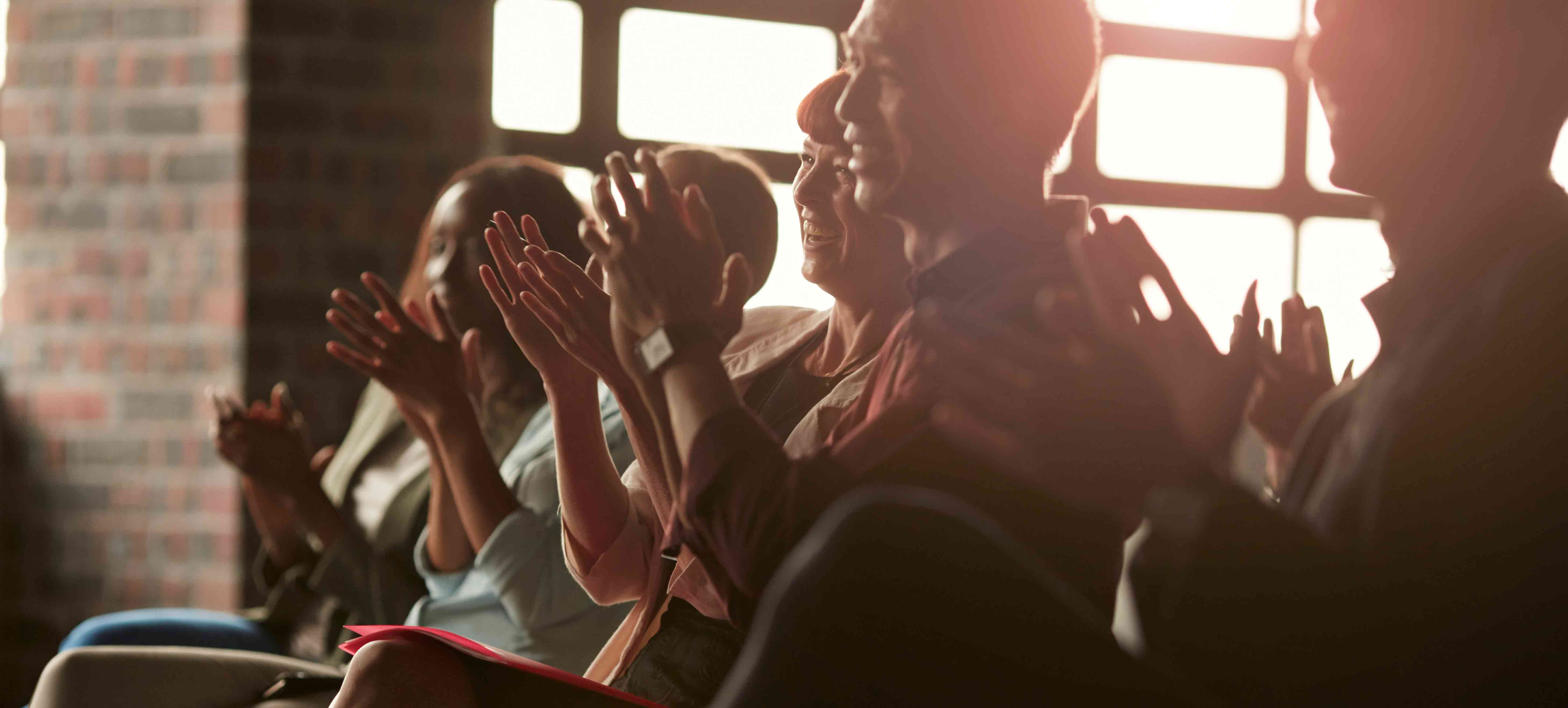 group-of-employees-applauding-while-sunlight-streams-in