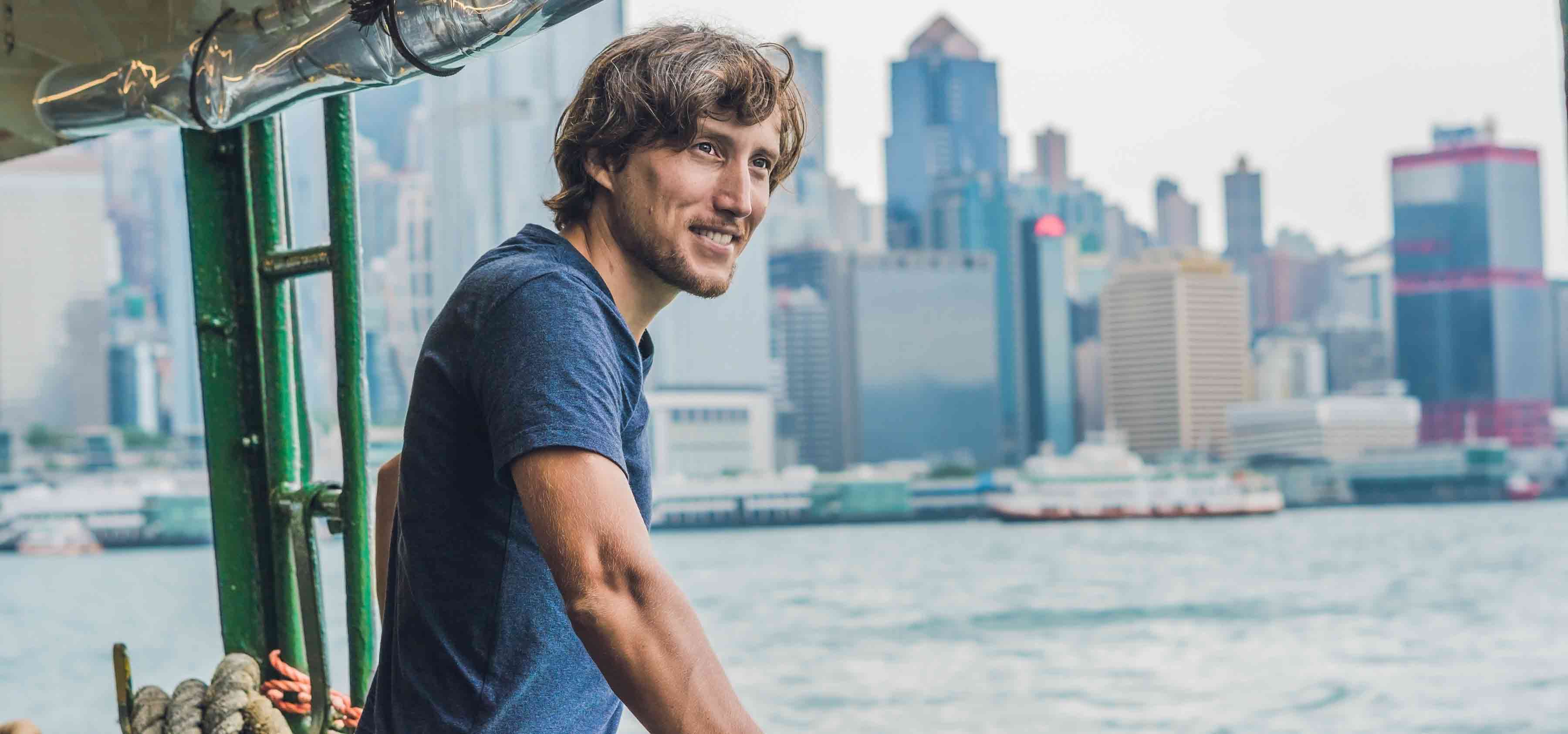 Man-looking-out-from-boat-with-skyline-in-the-background