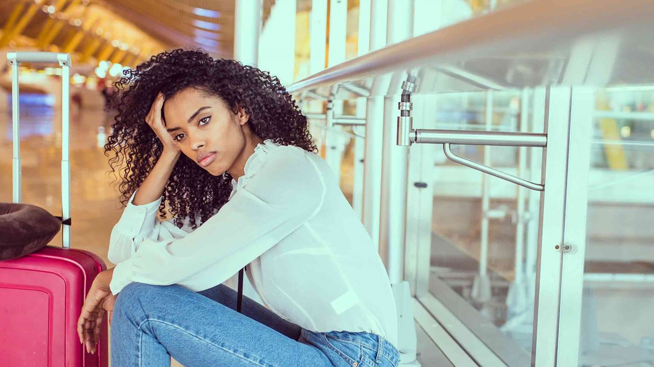 pensive-woman-sitting-next-to-luggage-at-the-airport
