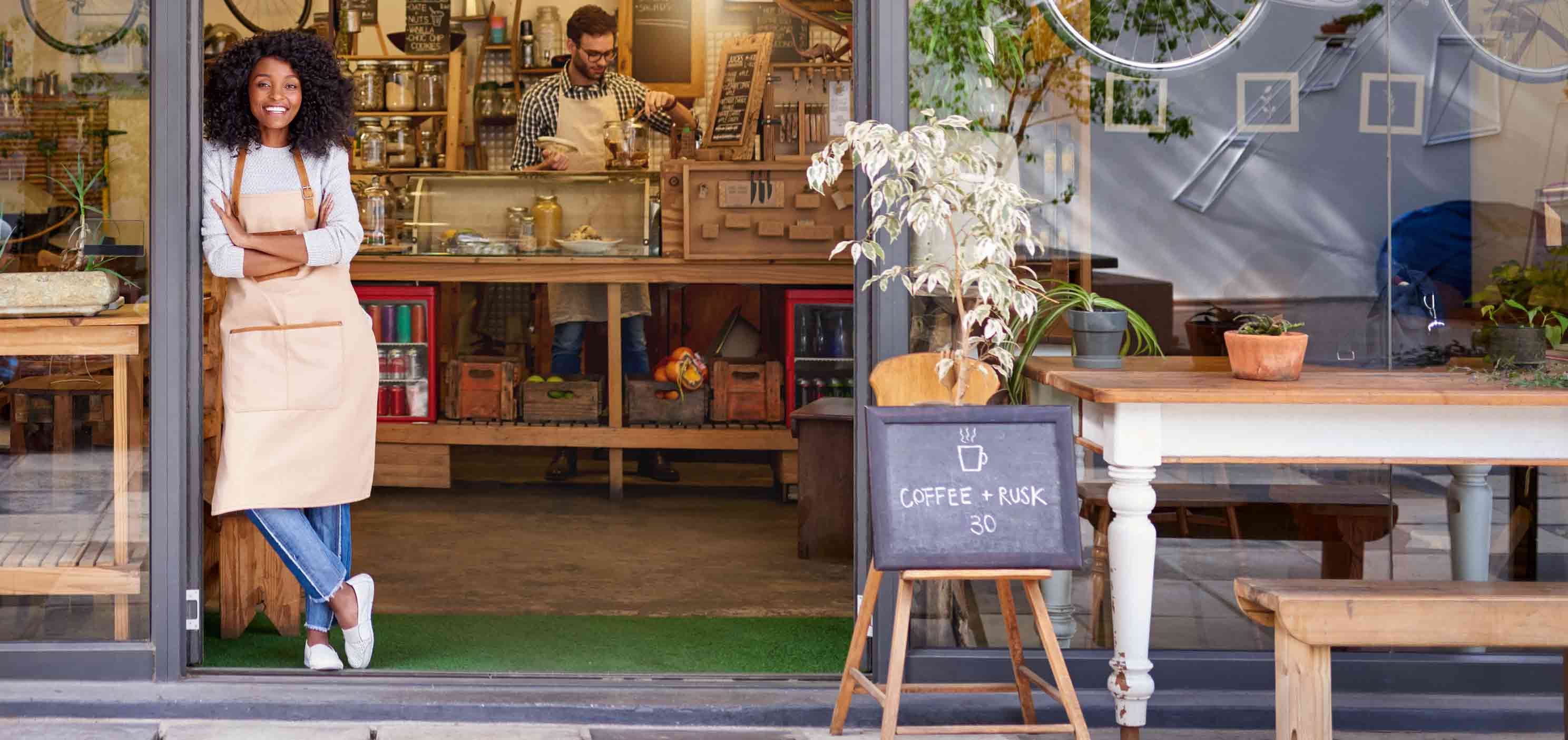 Woman-standing-at-the-door-of-a-small-business-looking-proud