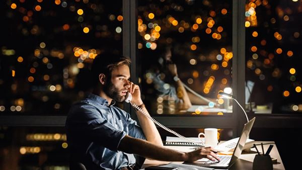 Man on phone in office with evening city view