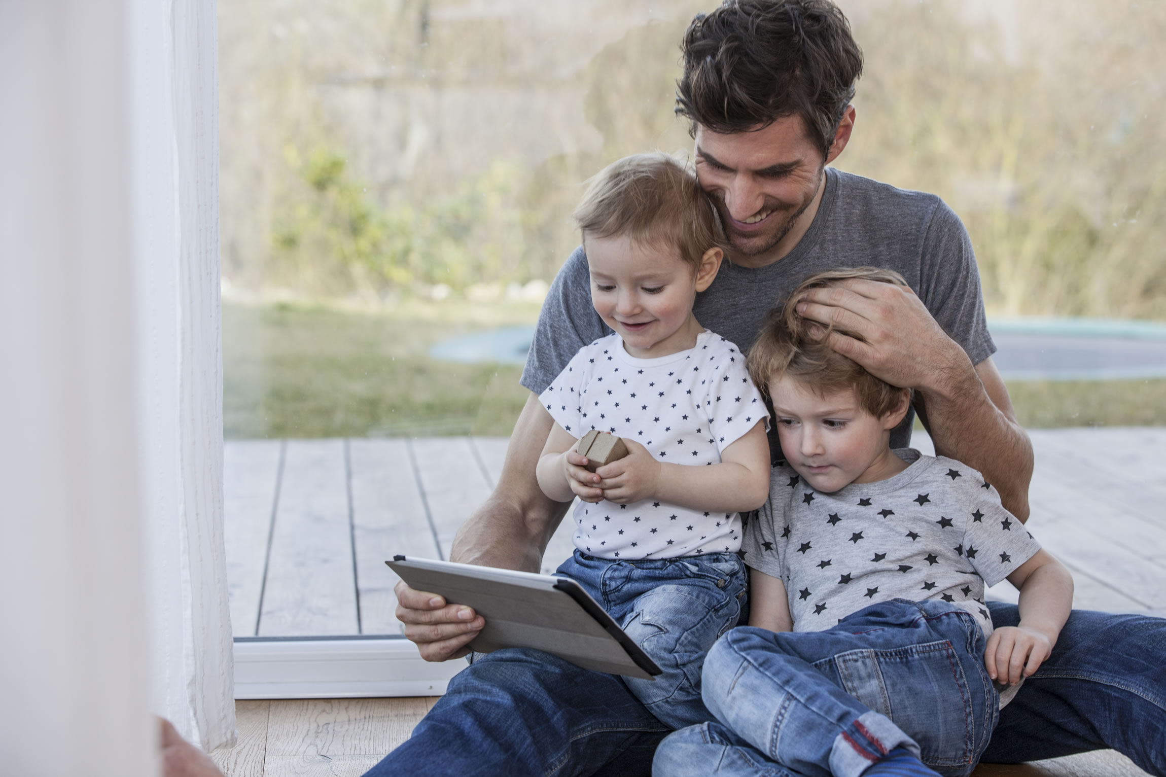 Father and sons looking at tablet device