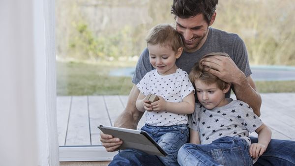 Father and sons looking at tablet device
