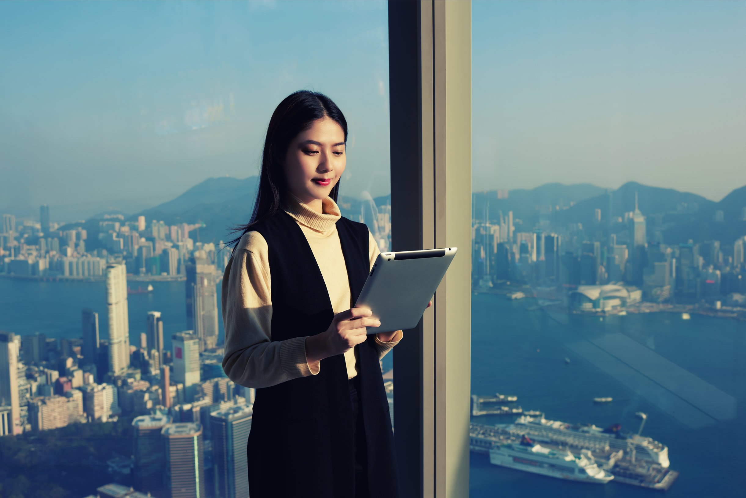 Business lady looking at device with city backdrop