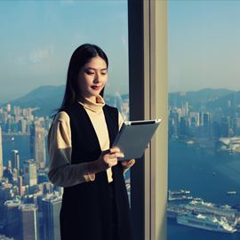Business lady looking at device with city backdrop