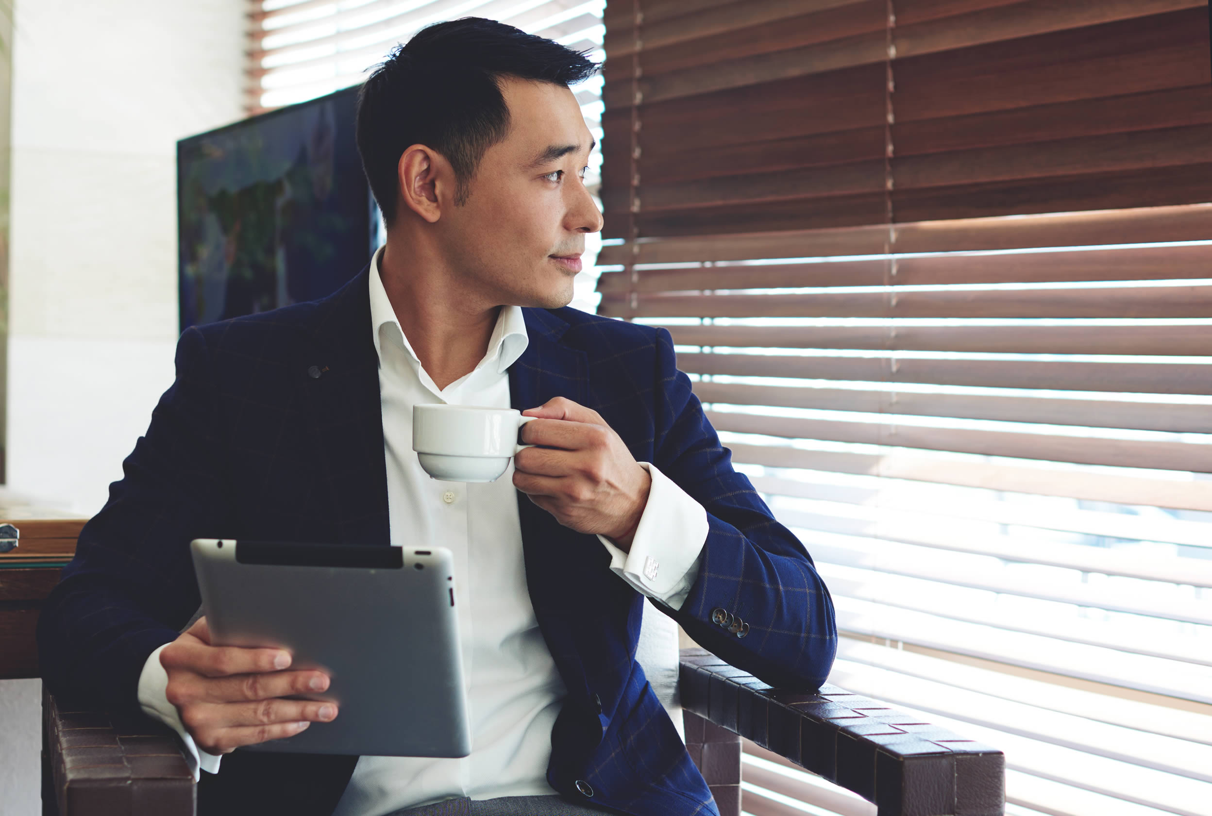 Business man drinking coffee while looking out window.