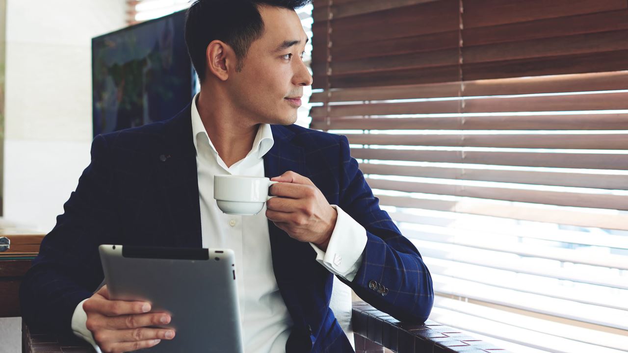 Business man drinking coffee while looking out window.