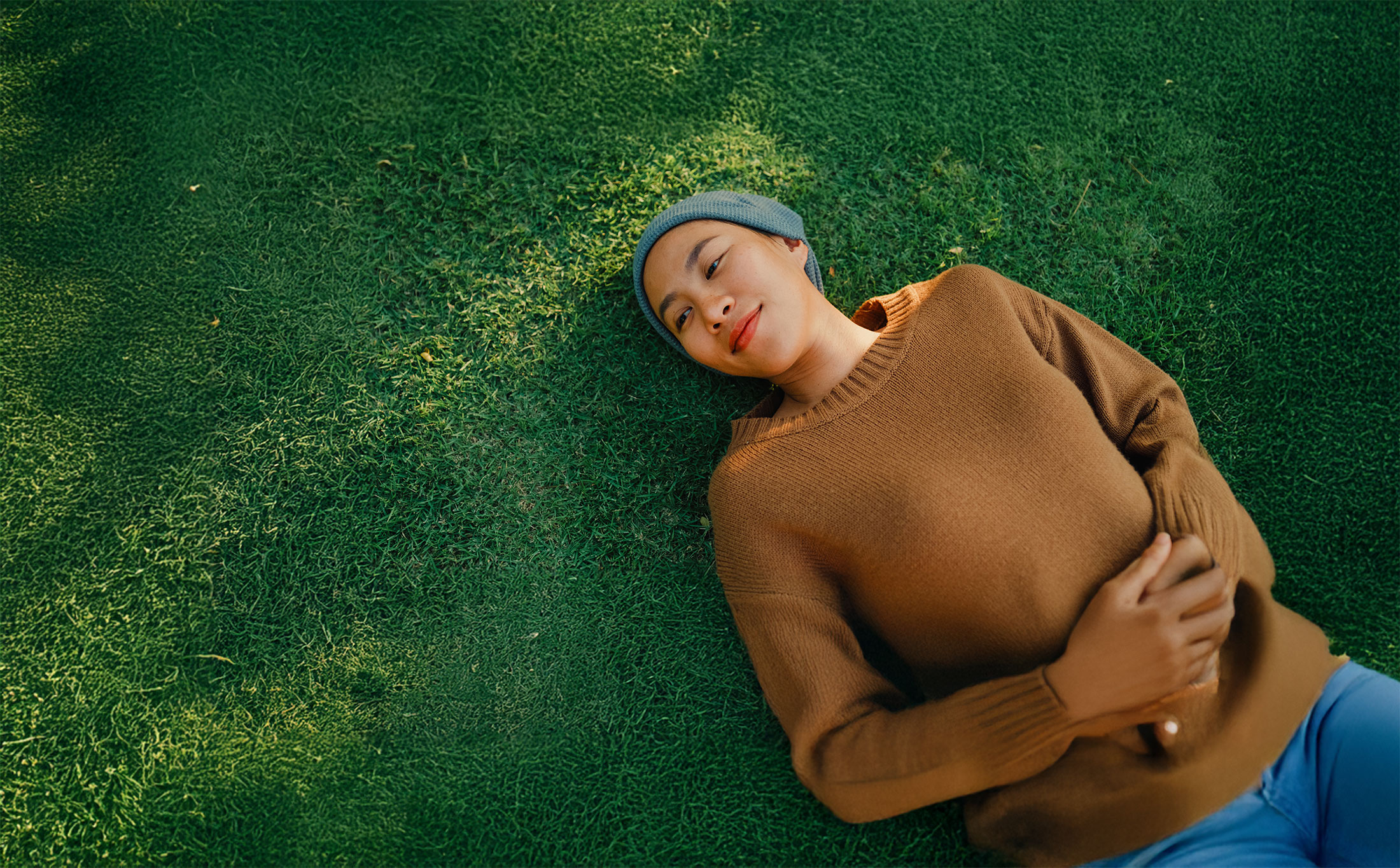 Closeup of young Asian woman sick with cancer rests on grass, taking a moment to relax