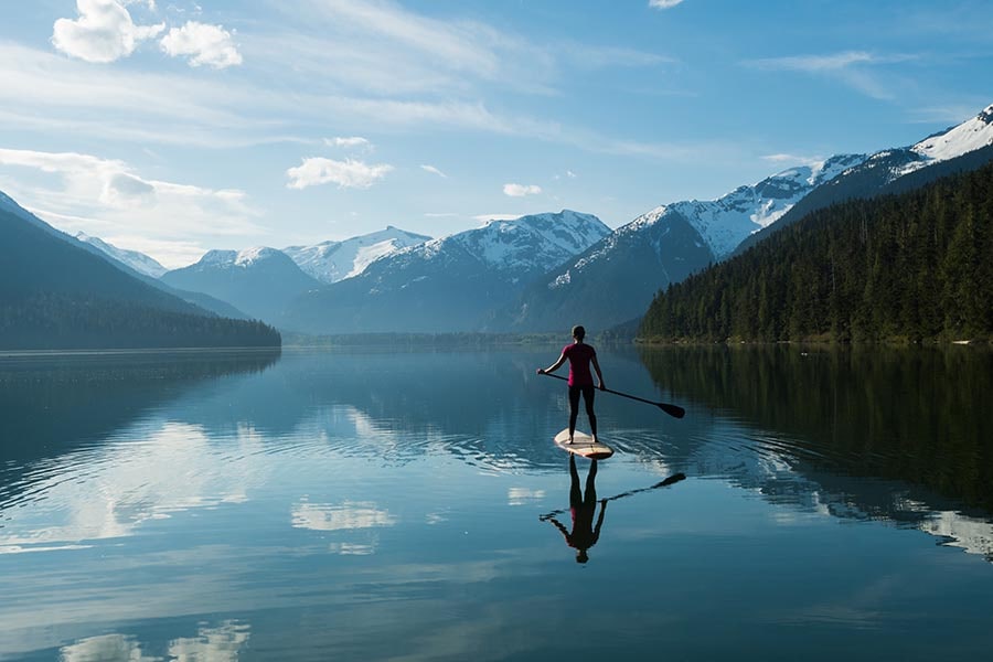 Woman paddleboarding with views of mountains