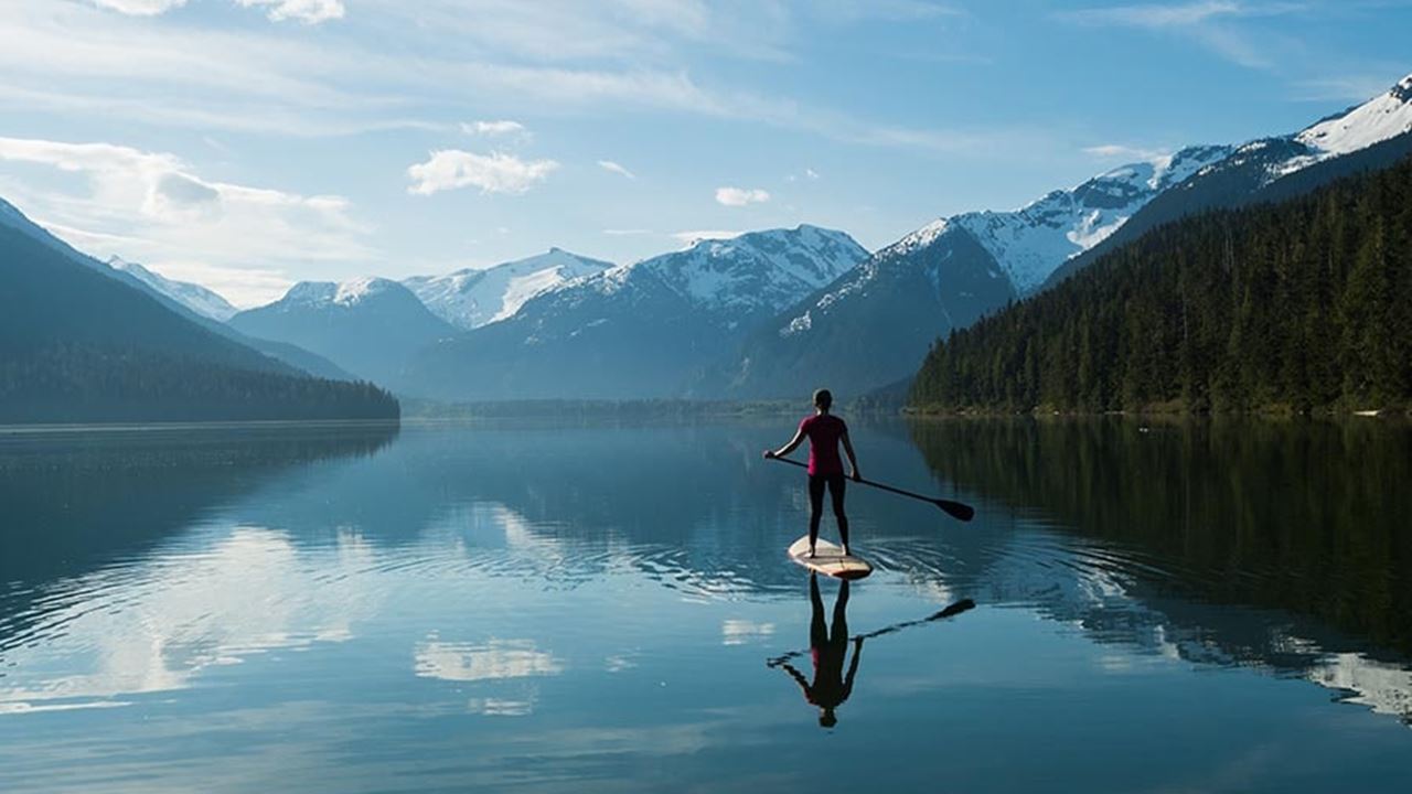 Woman paddleboarding with views of mountains