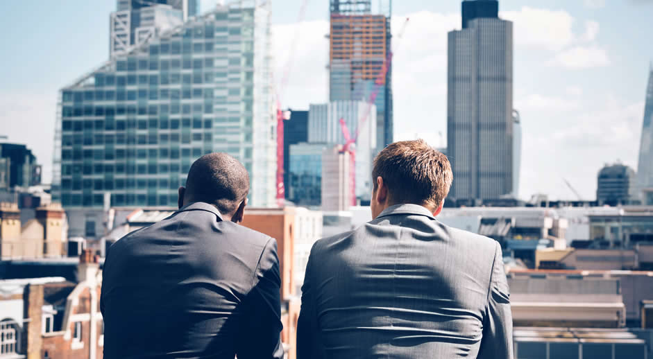 Two businessman looking out across city