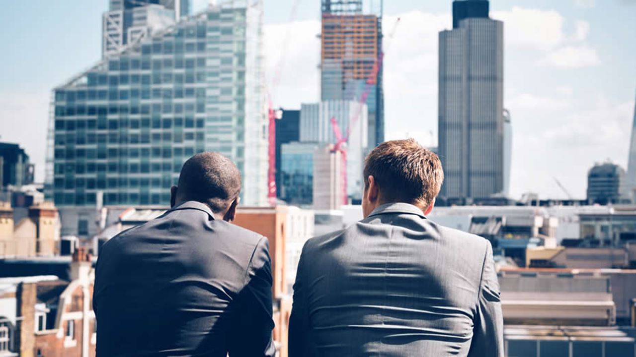 Two businessman looking out across city