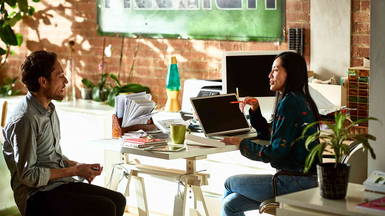 man and woman speaking in vibrant office