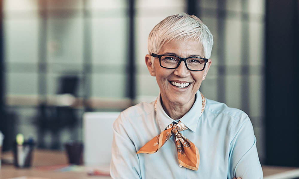 older woman in office attire and glasses smiling