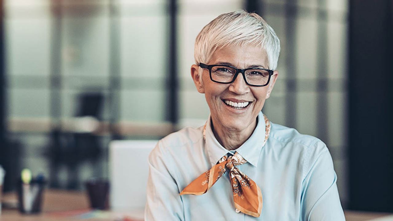 older woman in office attire and glasses smiling