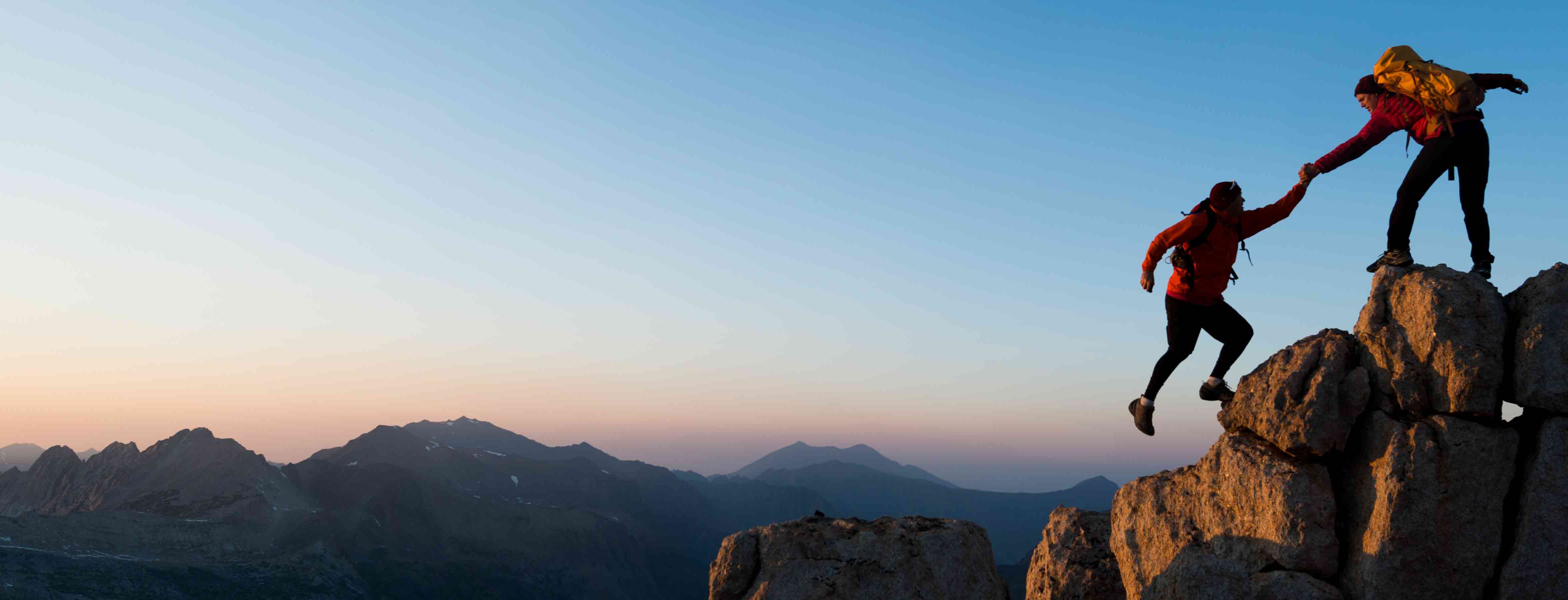 person helping someone up a mountain