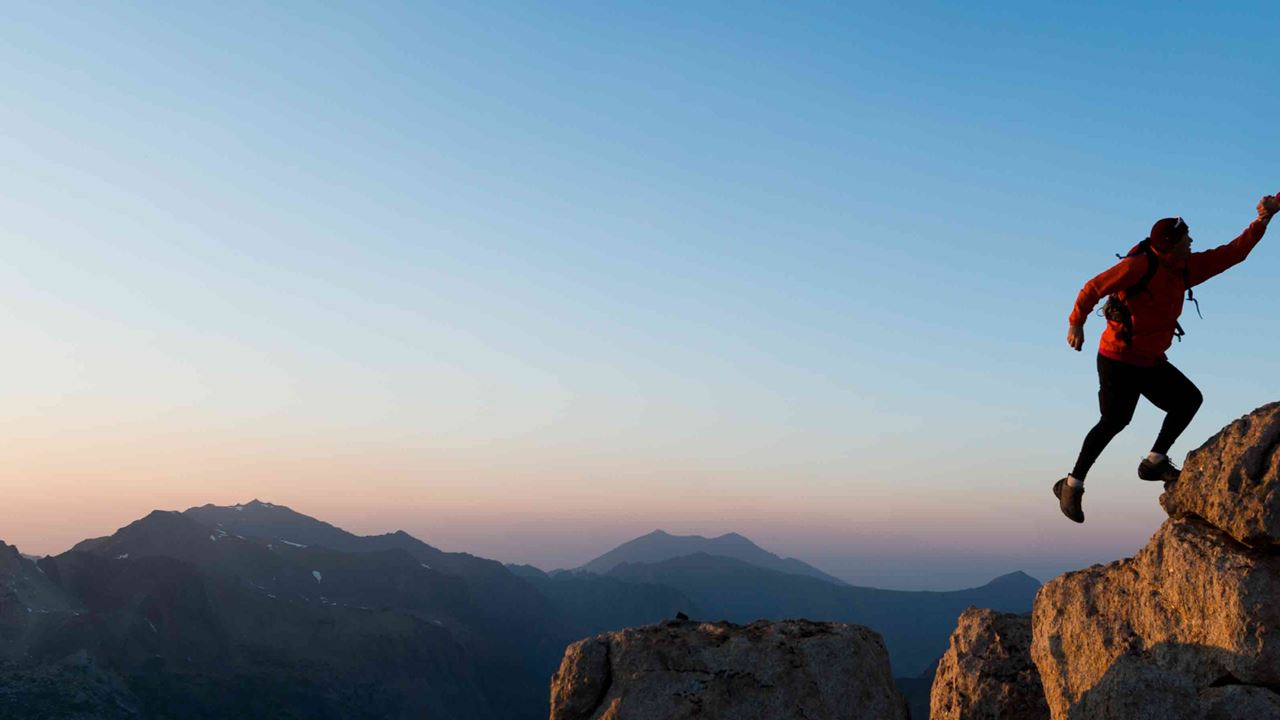 person helping someone up a mountain