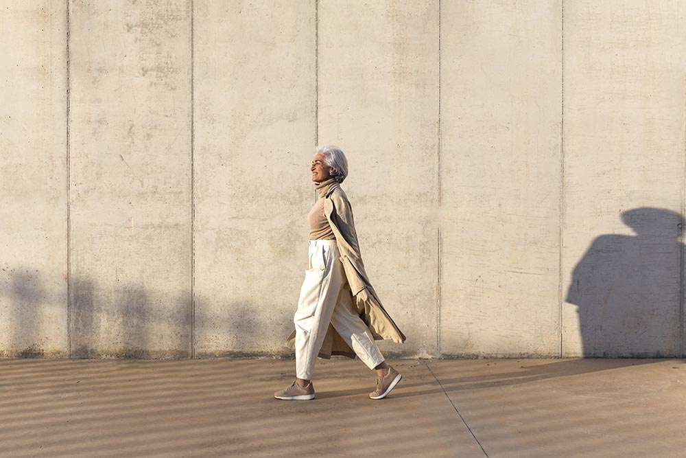 smiling silver-haired woman walking in the sun