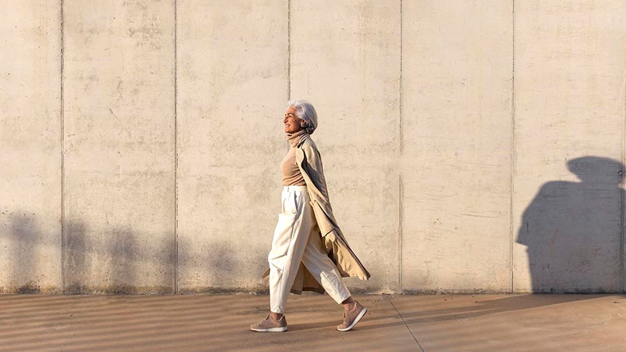 smiling silver-haired woman walking in the sun