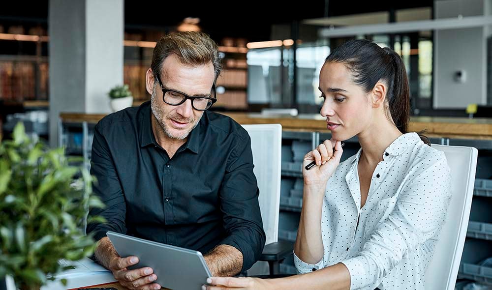 Man and woman in office discussing over a tablet
