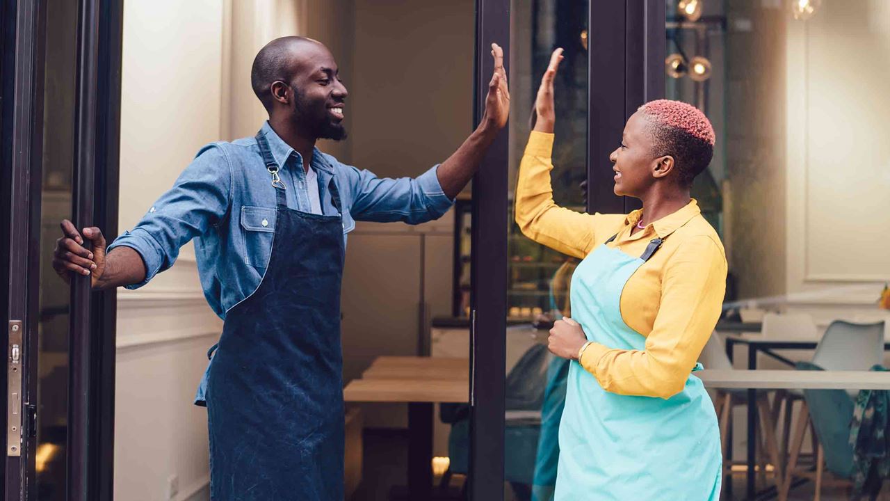 Man and woman hi fiving in front of shop