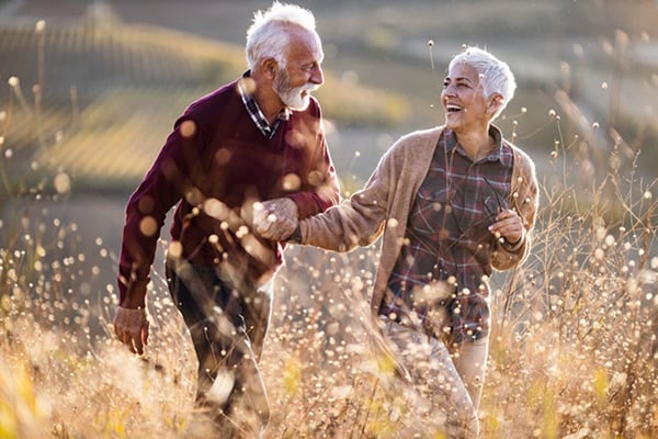elderly couple laughing in a field