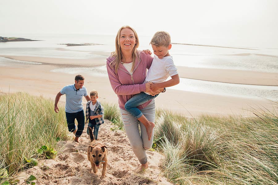 family walking on beach with dog