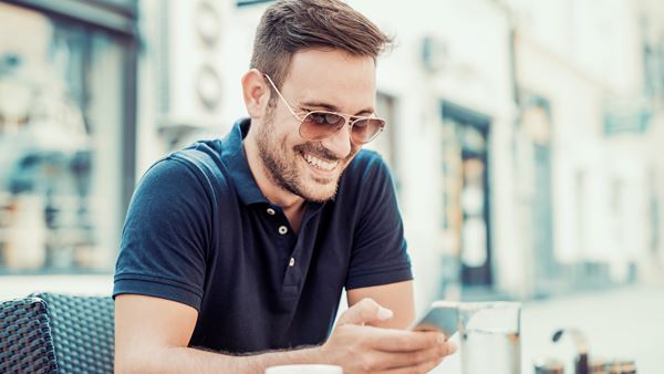 Man smiling in coffee shop using phone