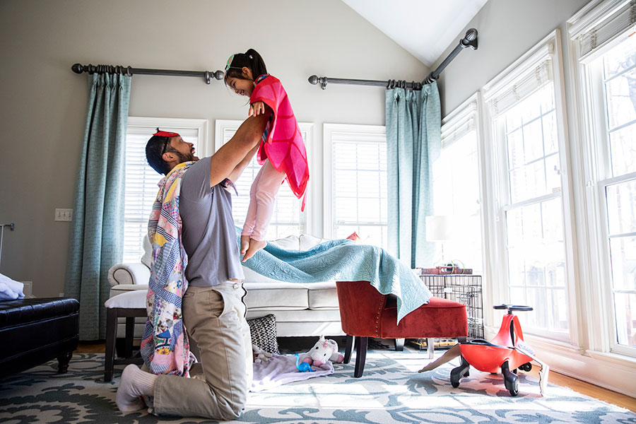 parent holding up child in house