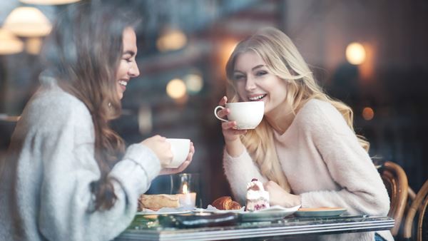 Two women laughing having tea and cake