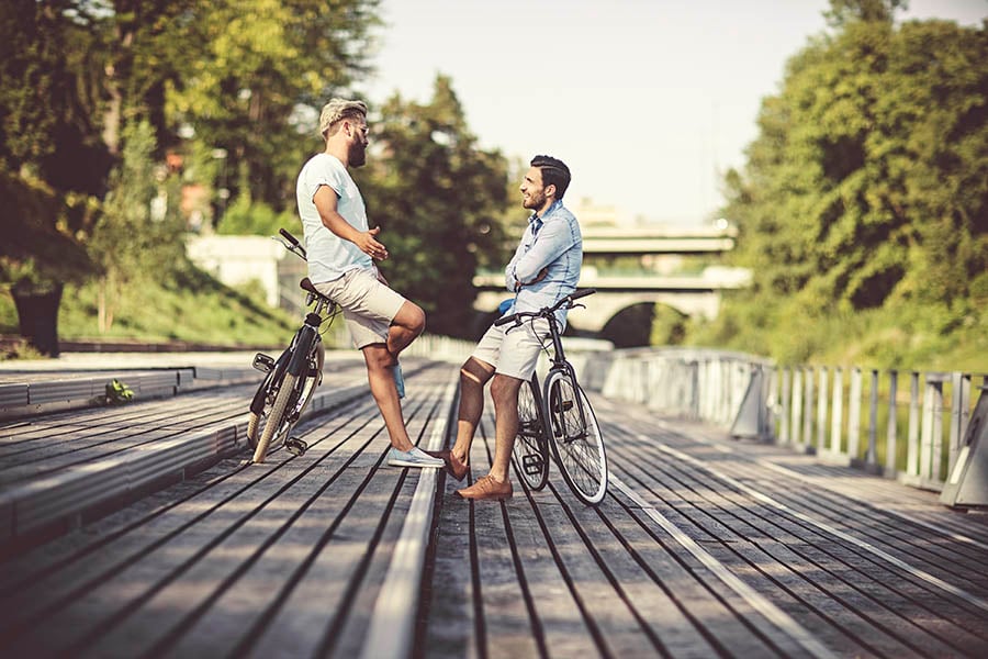 Two men chatting outside with bikes