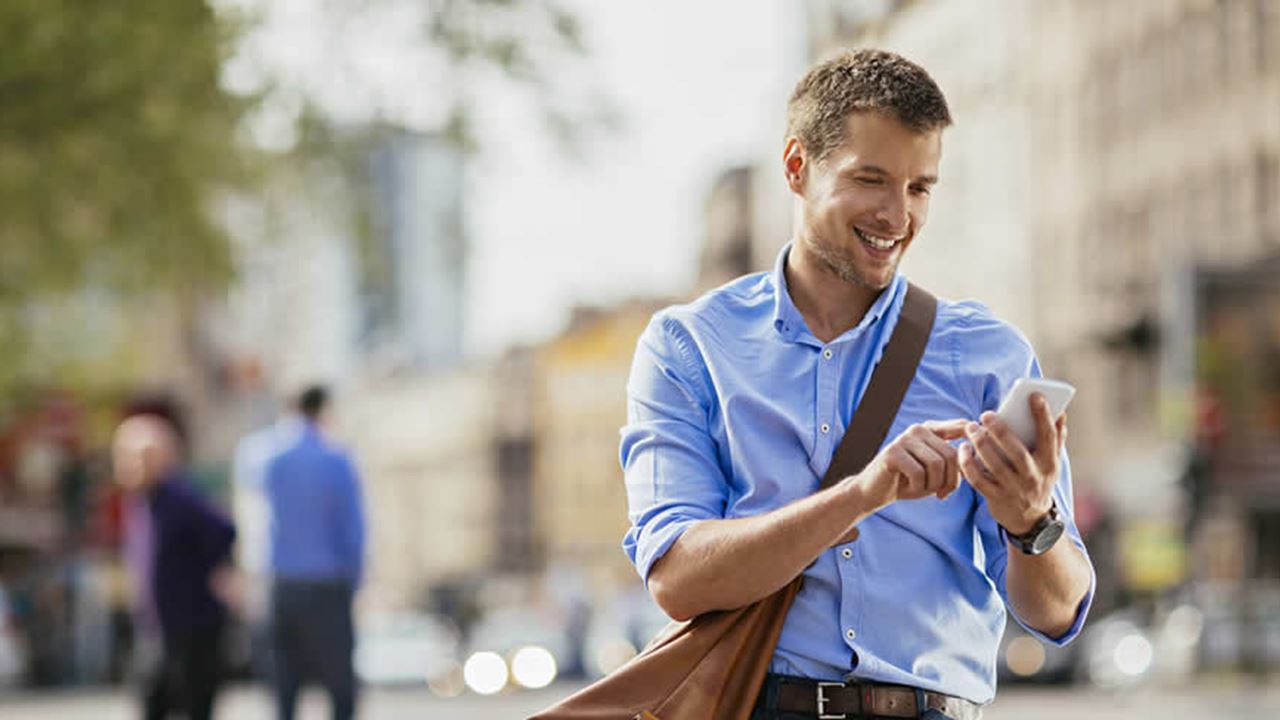 Smartly dressed man smiling while using his phone