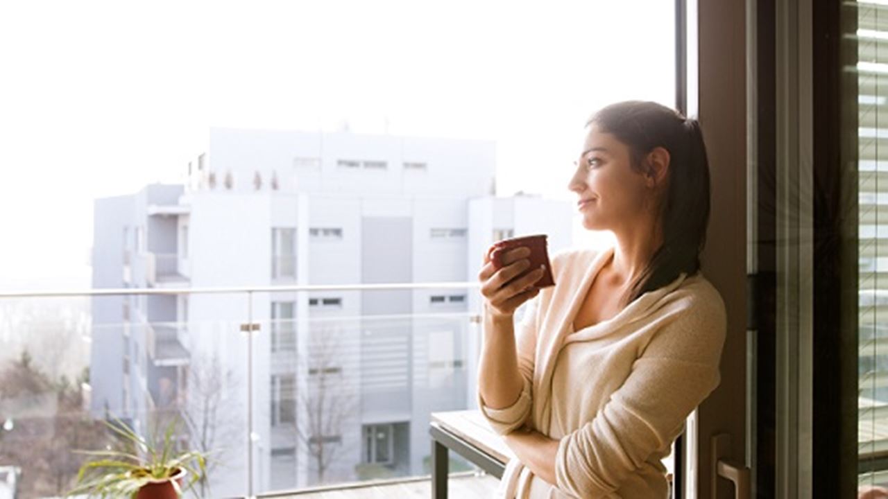 Woman with cup of coffee looking out over city