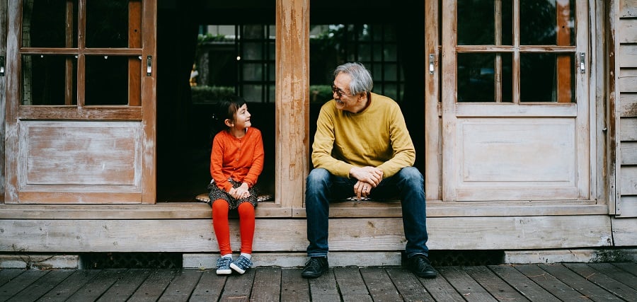 Grandfather and granddaughter sat on step talking