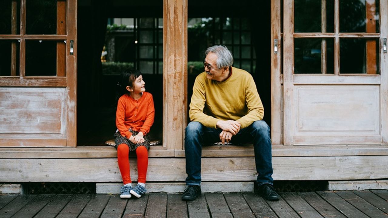 Grandfather and granddaughter sat on step talking