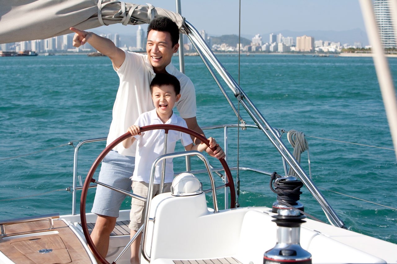 Father and son smiling and sailing on a yacht