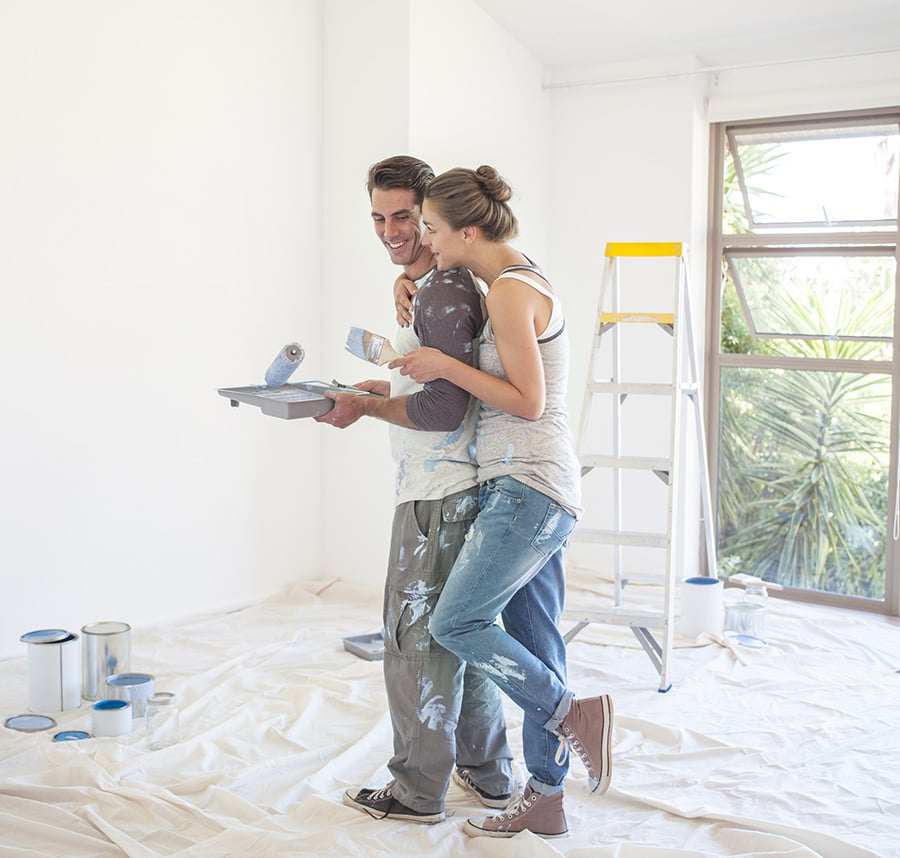 Happy couple painting new house walls