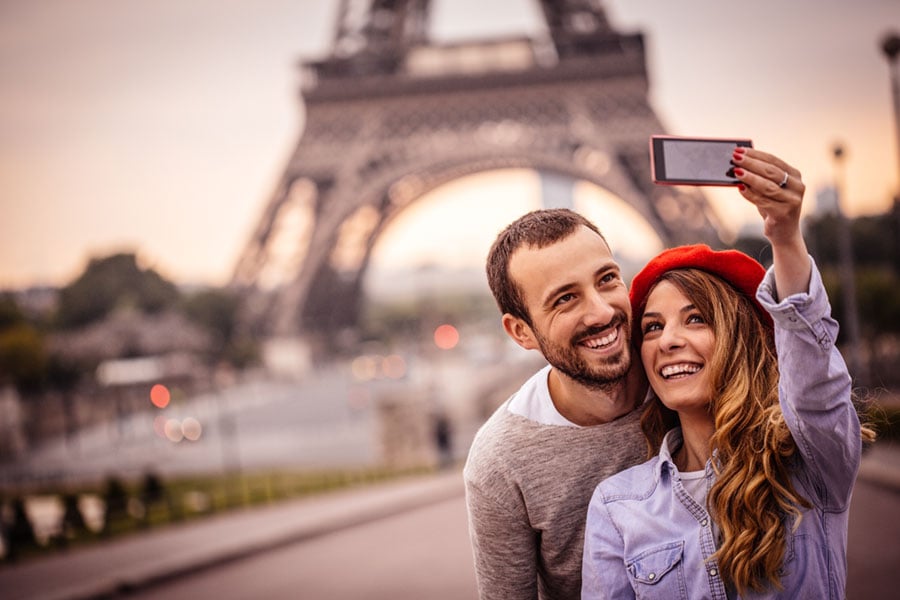 a happy young couple taking a selfie in front of the Eiffel tower
