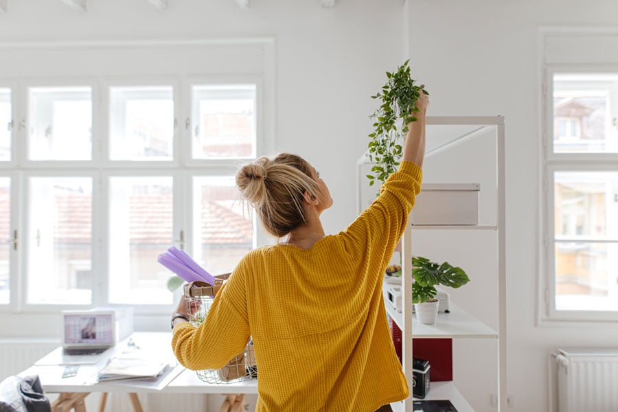 woman arranging plants in her stylish new apartment