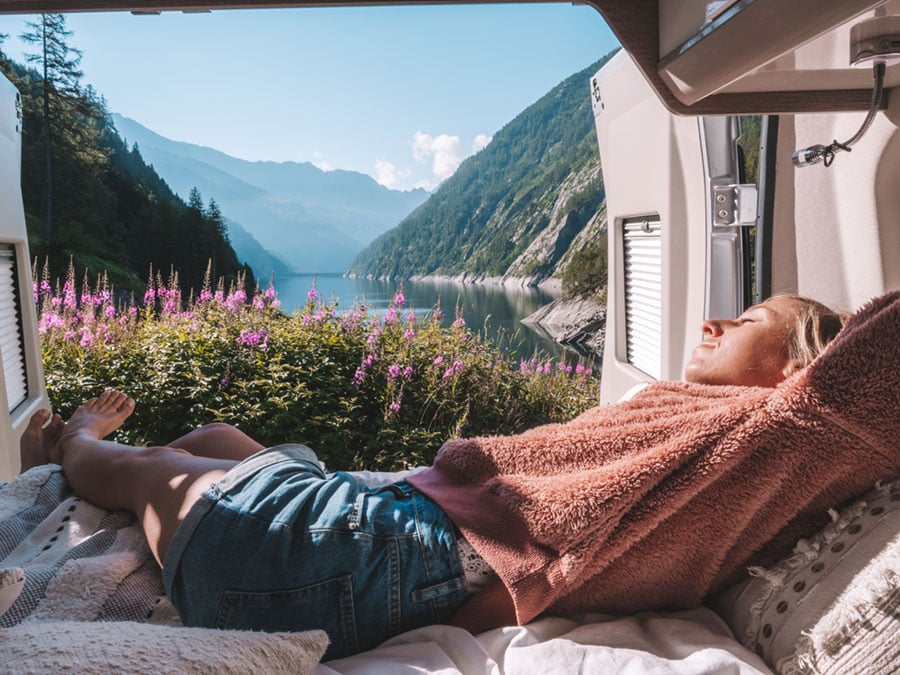 woman laying in van with mountainous scenery behind