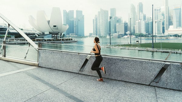 female jogging on a bridge with Singapore in the back