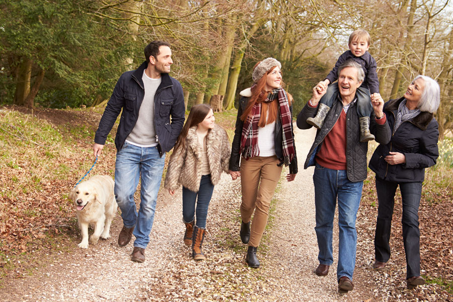 extended family walking their dog on an autumn wood path