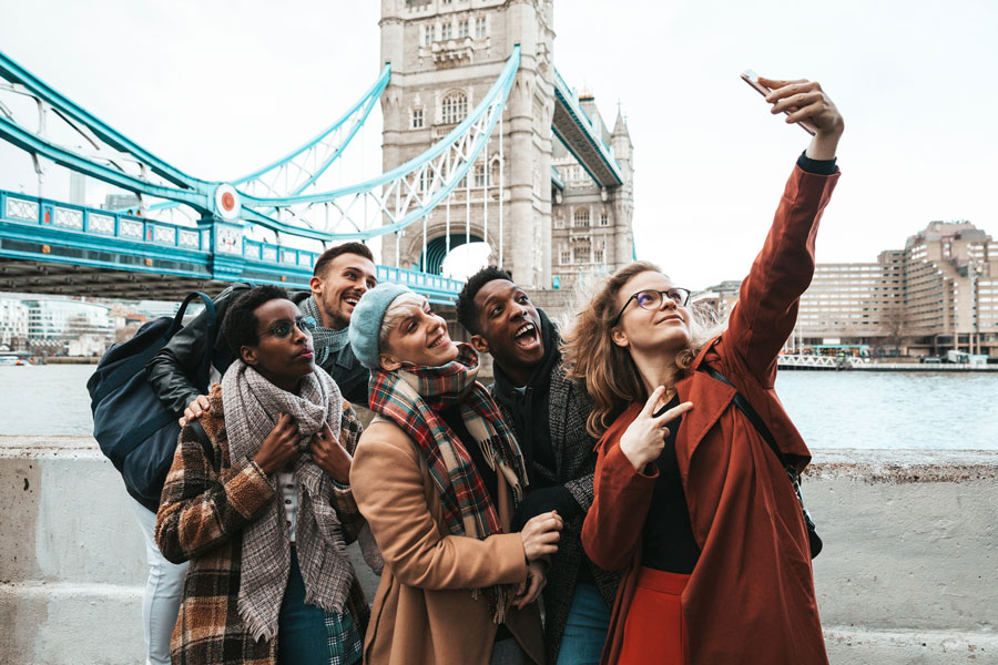 a group of multicultural friends taking a selfie near Tower bridge