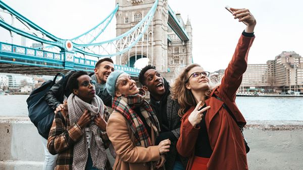 a group of multicultural friends taking a selfie near Tower bridge