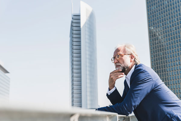 pensive mature businessman on a rooftop with skyscraper behind