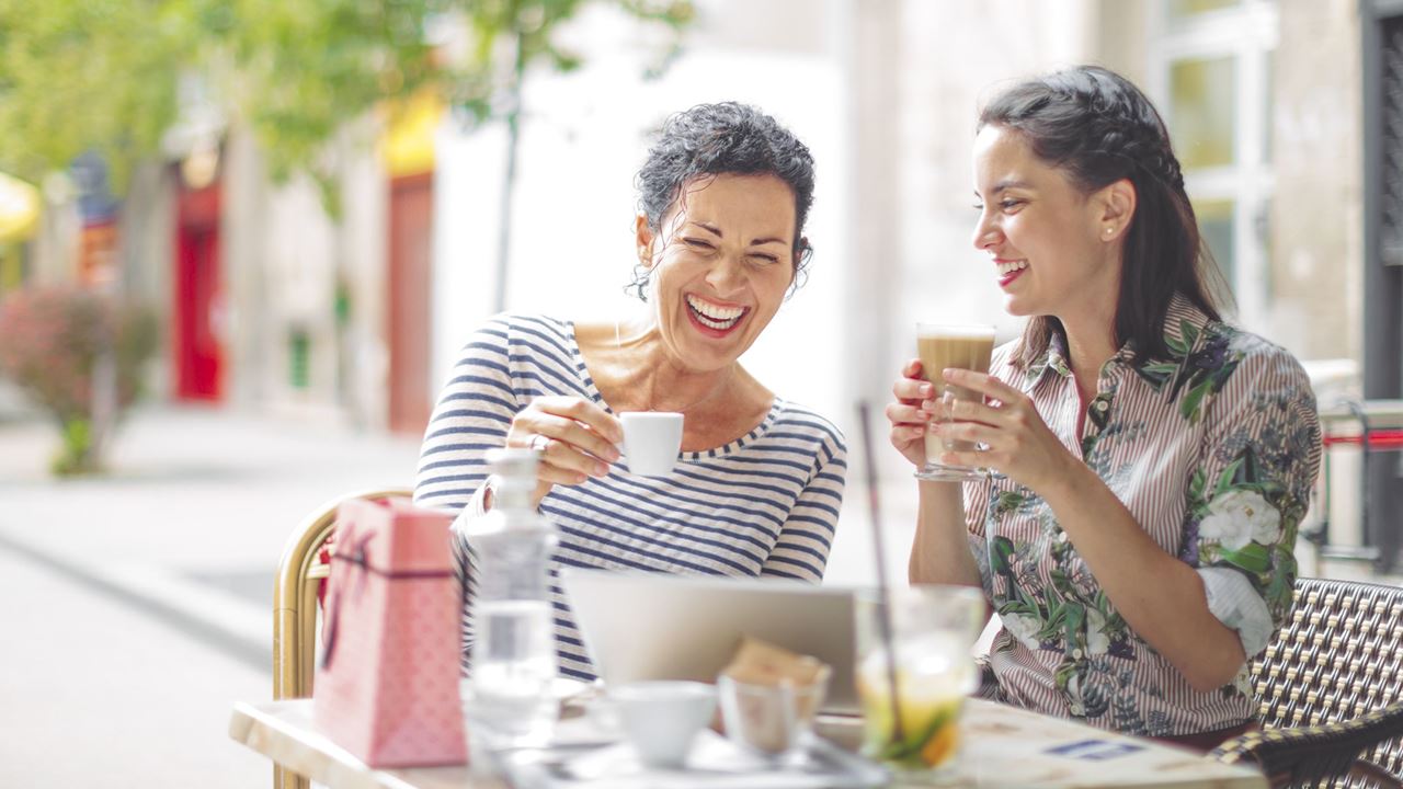 Two women laughing over coffee